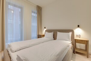 Habitación de hotel con una cama grande, dos mesitas de noche y una lámpara de pared.