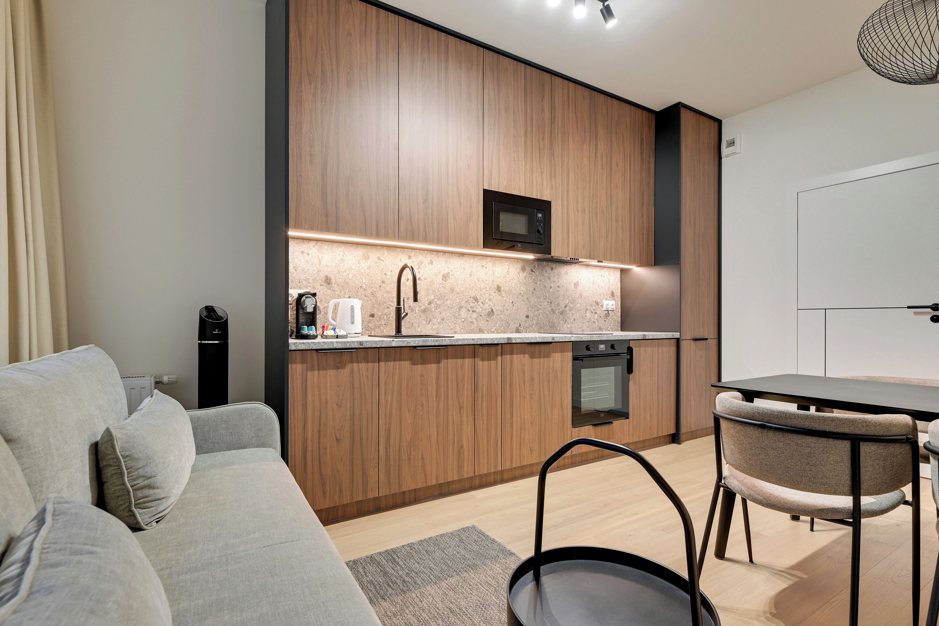 Una cocina moderna con armarios de madera, microondas integrado y cafetera.