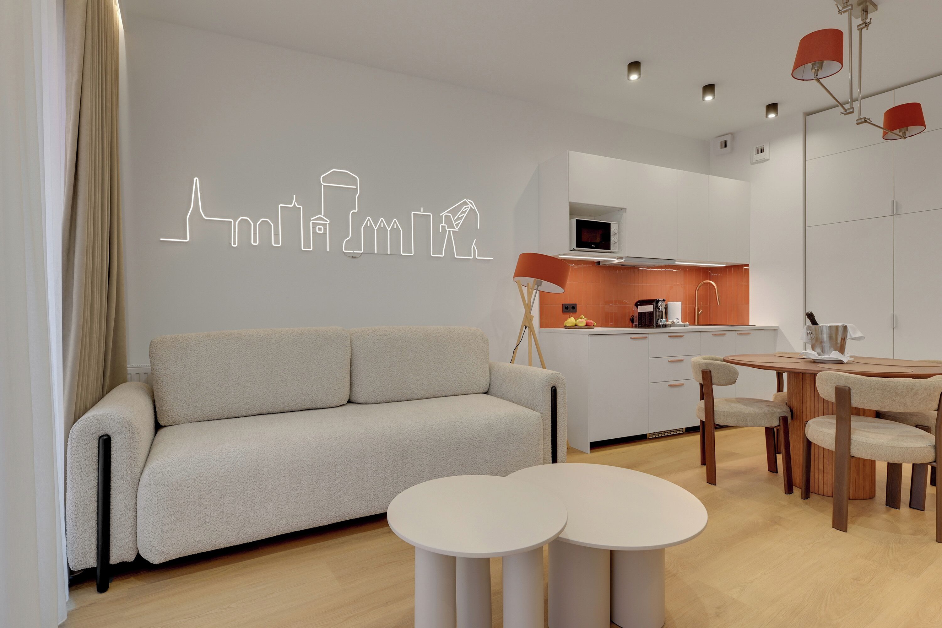 A modern living room with a sofa, two round tables, and a dining area with chairs.