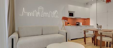 A modern living room with a sofa, two round tables, and a dining area with chairs.