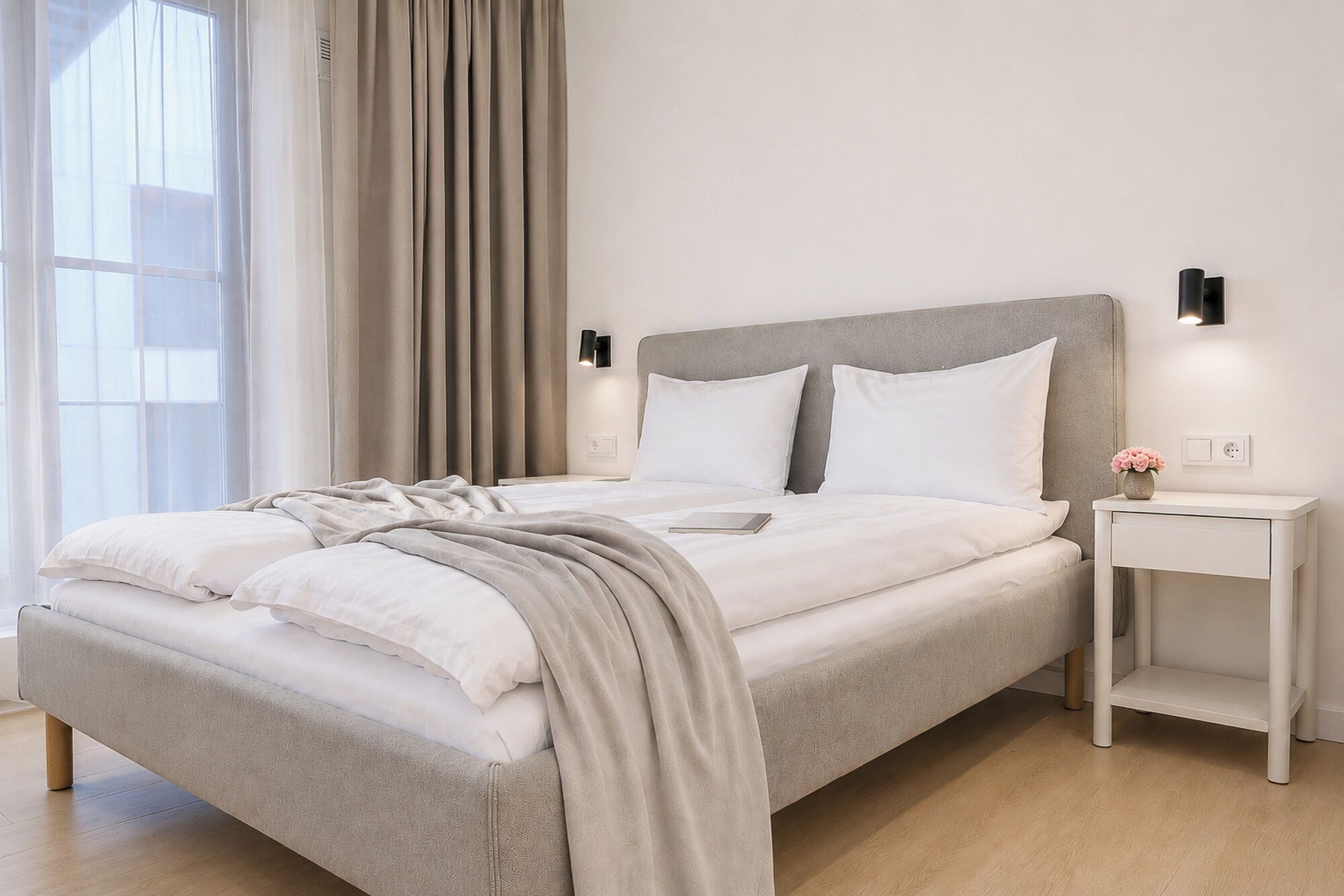 A modern bedroom with a large bed, a bedside table, and a nightstand.