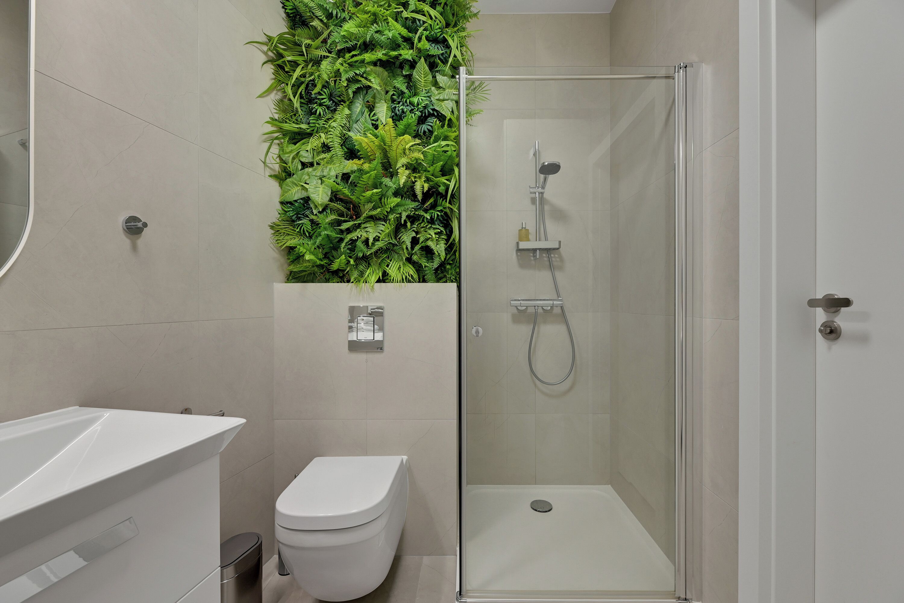 A modern bathroom with a glass-enclosed shower, a white toilet, and a sink with a mirror.