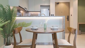 Una cuina moderna amb una illa central, il·luminació penjant i una zona de dinar amb taula rodona i seients.