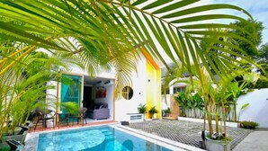 A swimming pool with a sunken center, surrounded by palm trees and a white building with a glass door. - Lux Sila Pool Villa 3 Bedrooms 4 Beds (Koh Samui)