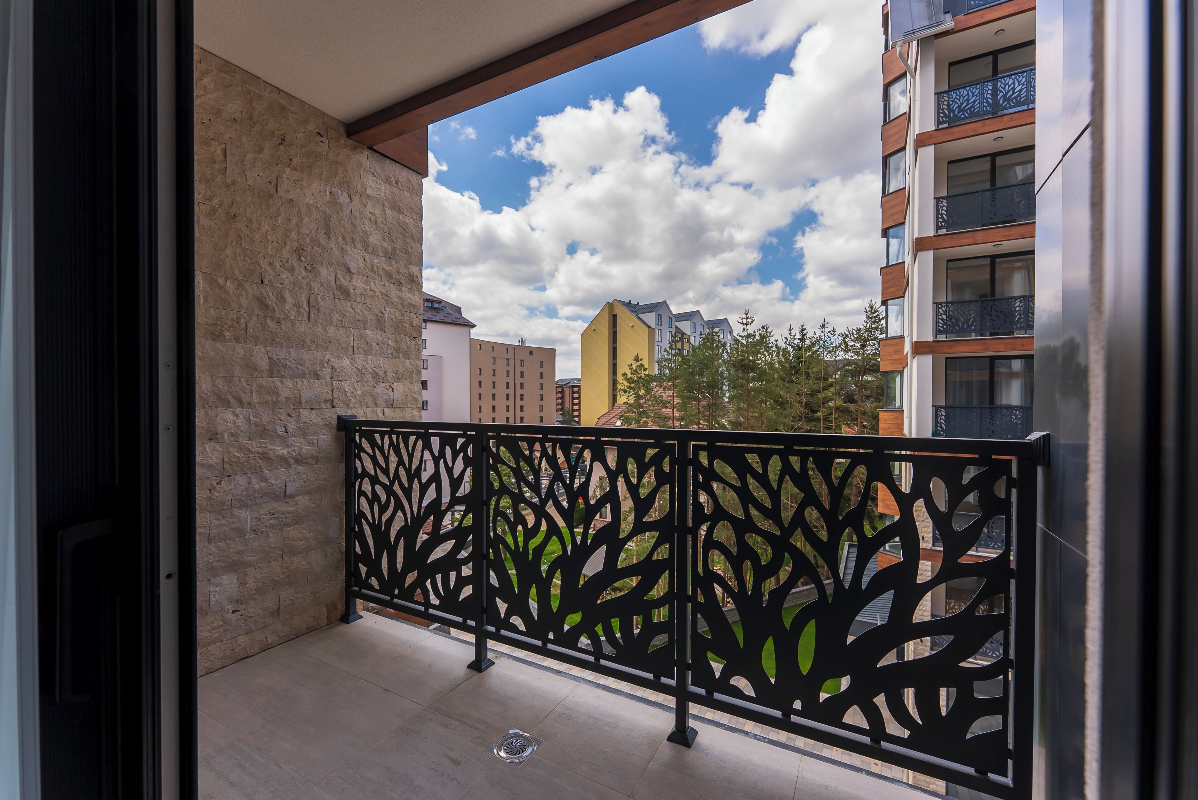 Ein Balkon mit schmiedeeisernem Geländer, einer Steinmauer und Blick auf die umliegenden Gebäude.