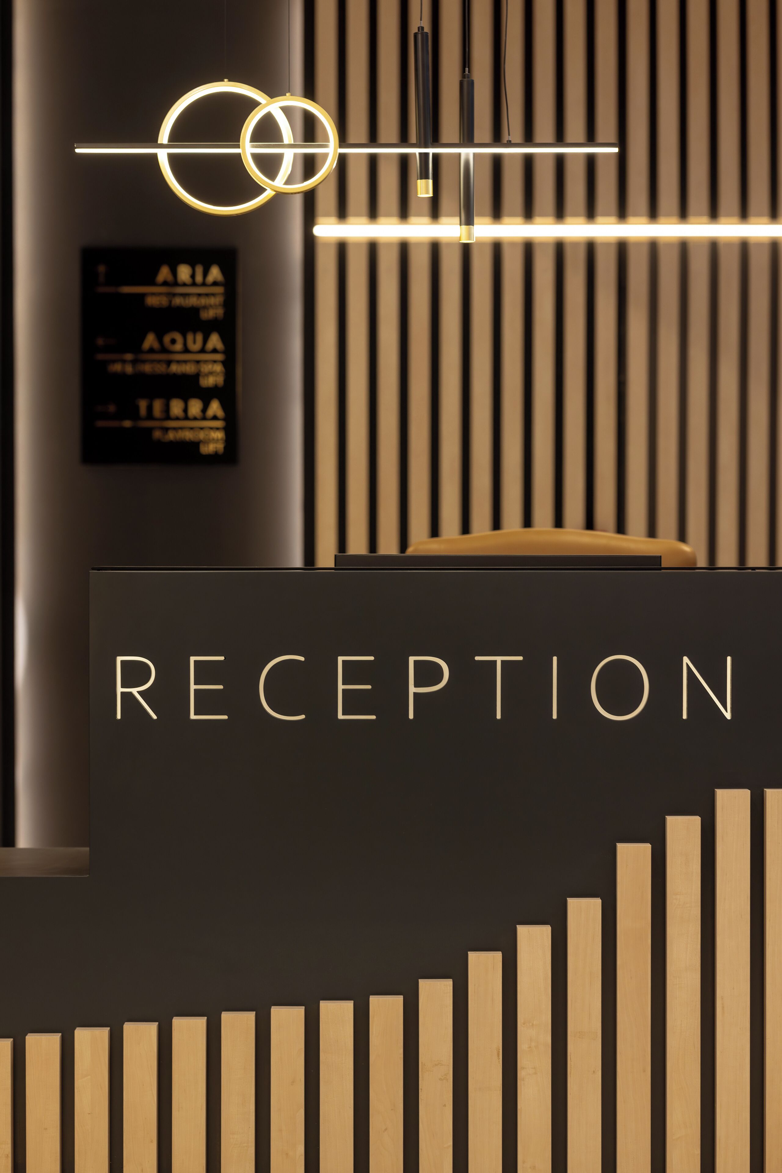 A reception desk with a sign that reads "RECEPTION" and a vertical wooden slat design below it.
