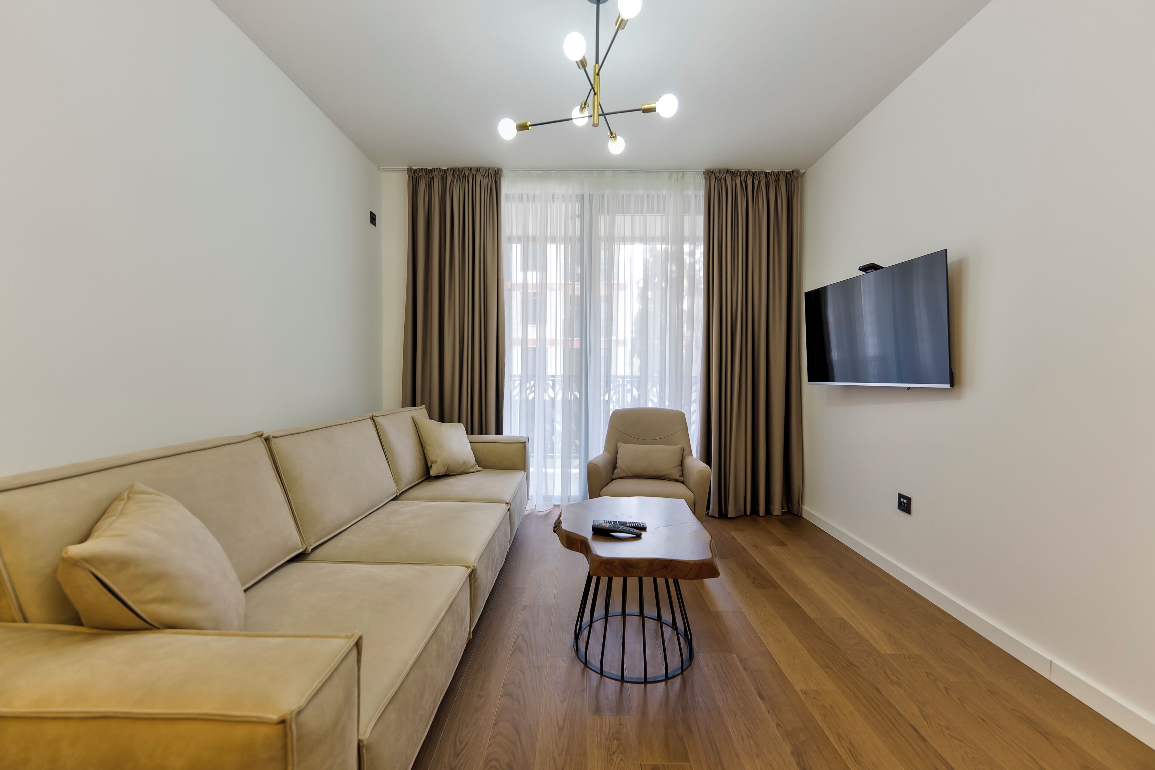A modern living room with a sofa, armchair, coffee table, and a TV mounted on the wall.