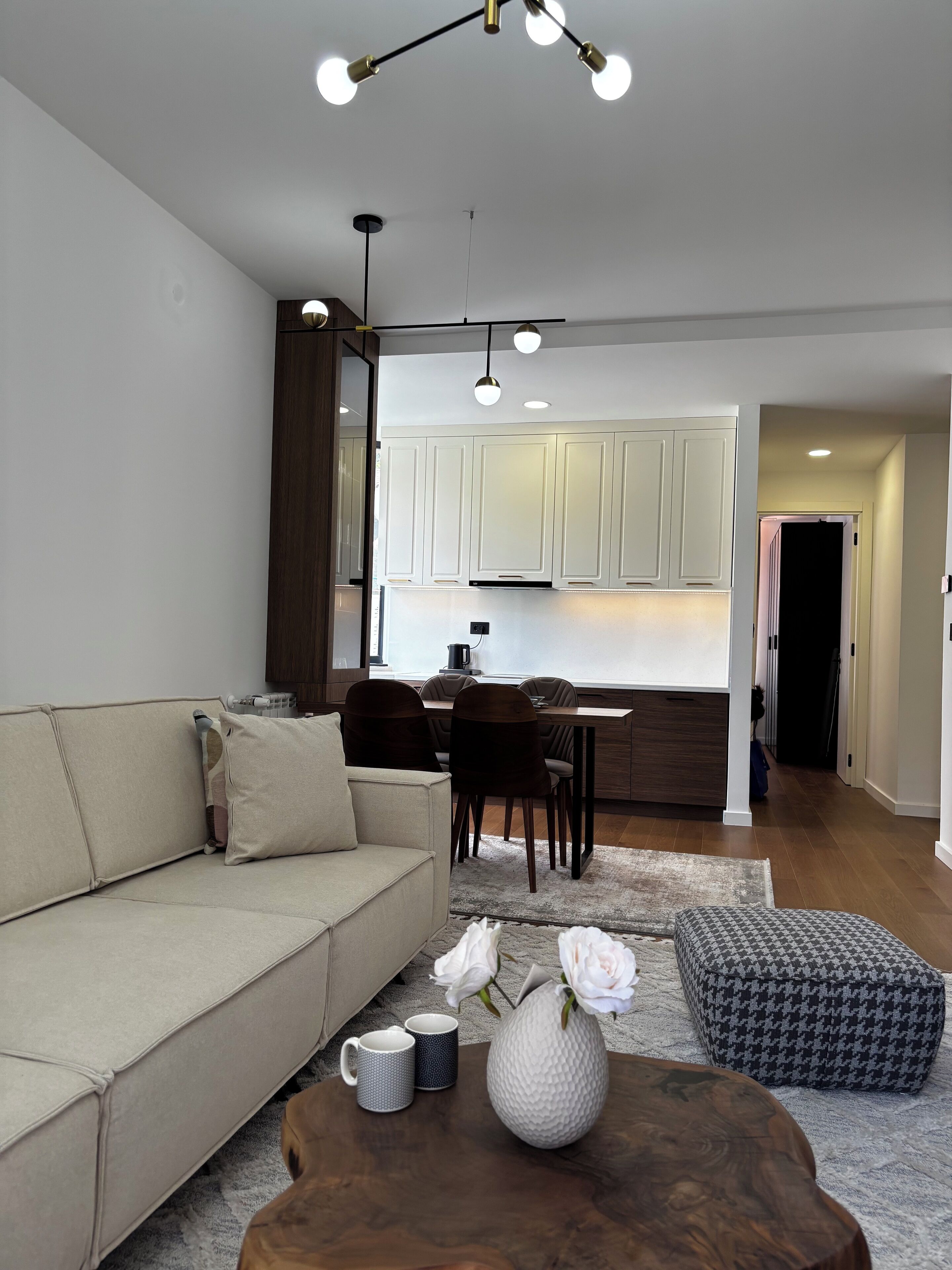 Uma sala de estar moderna com sofá, mesa de centro e área de jantar com cadeiras e mesa.