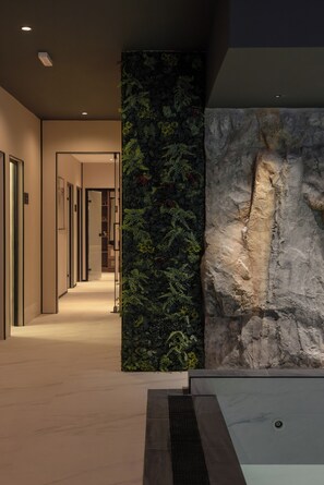 A modern interior with a hallway leading to rooms, a vertical garden wall, and a rock feature. - Modena Resort Spa & Wellness Zlatibor (Zlatibor)