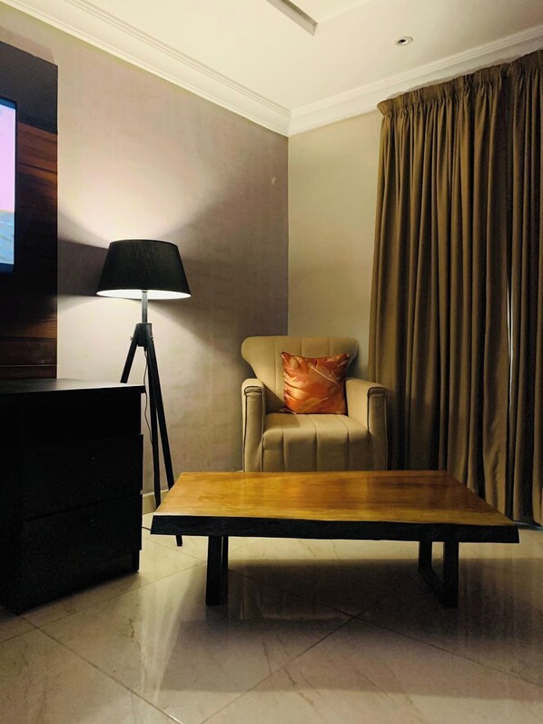 Un salon avec un canapé, une table basse, une lampe et un téléviseur.