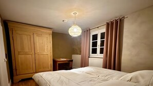 A bedroom with a bed, wooden wardrobe, a small table, and a window with curtains. - Apartment 'Groß' with Shared Garden and Wi-Fi (Offenburg)
