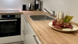 A kitchen with a wooden countertop, a sink, a coffee maker, and a plate of grapes. - Apartment 'Groß' with Shared Garden and Wi-Fi (Offenburg)