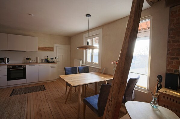 A modern kitchen with white cabinets, a wooden dining table, and blue chairs.