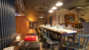 A restaurant with a long wooden table set for dining, chairs, a bookshelf, and a stone wall. - Apartment 'Klein' with Shared Garden and Wi-Fi (Offenburg)
