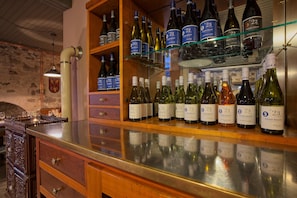 Una cava de vinos con estanterías llenas de botellas, armarios de madera y un mostrador de cristal.