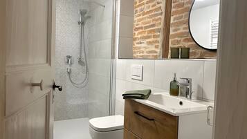 Een badkamer met een douche, toilet en wastafel met spiegel.