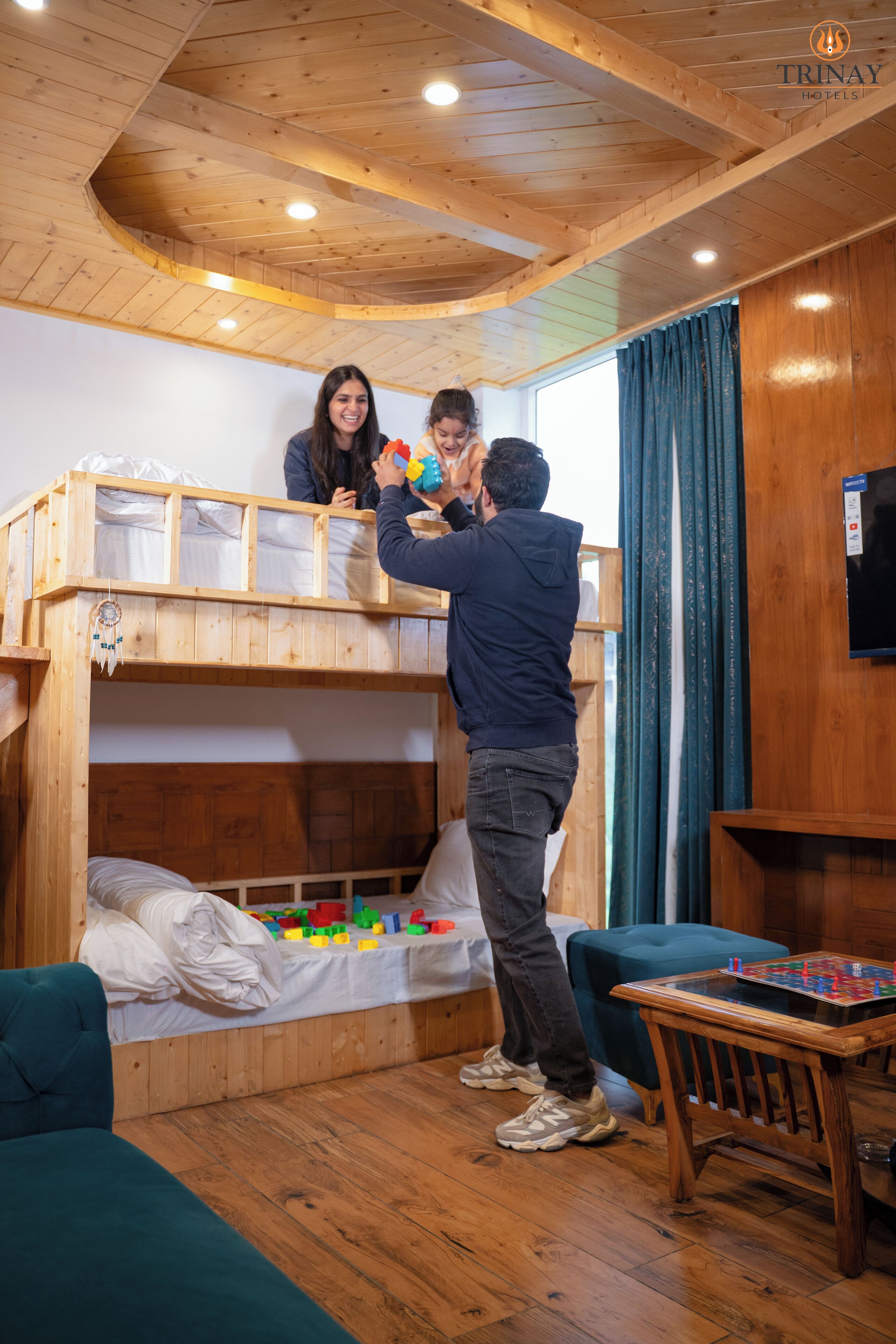A bunk bed room with wooden beams, a television, and a small table.