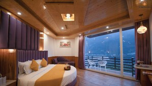 A large bed with a headboard, a small table with a bottle and glasses, and a balcony with chairs. - White Season Resort (Manali)