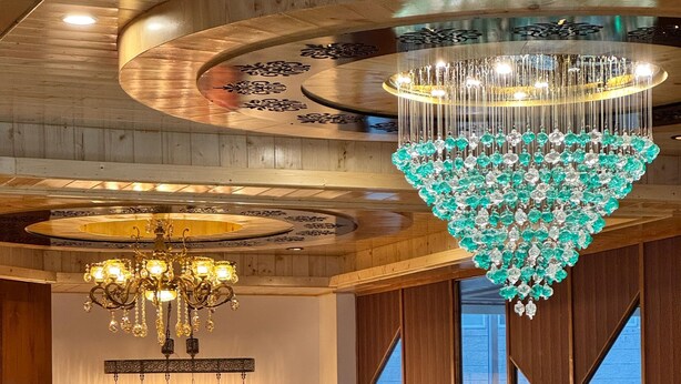 A reception area with a reception desk, a sofa, a glass coffee table, and a chandelier. - White Season Resort (Manali)
