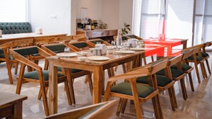 A dining area with wooden tables and chairs, a buffet setup, and a view of the outside through large windows. - White Season Resort (Manali)