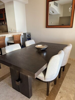 Un comedor con una mesa de madera oscura, seis sillas tapizadas y un espejo grande en la pared.