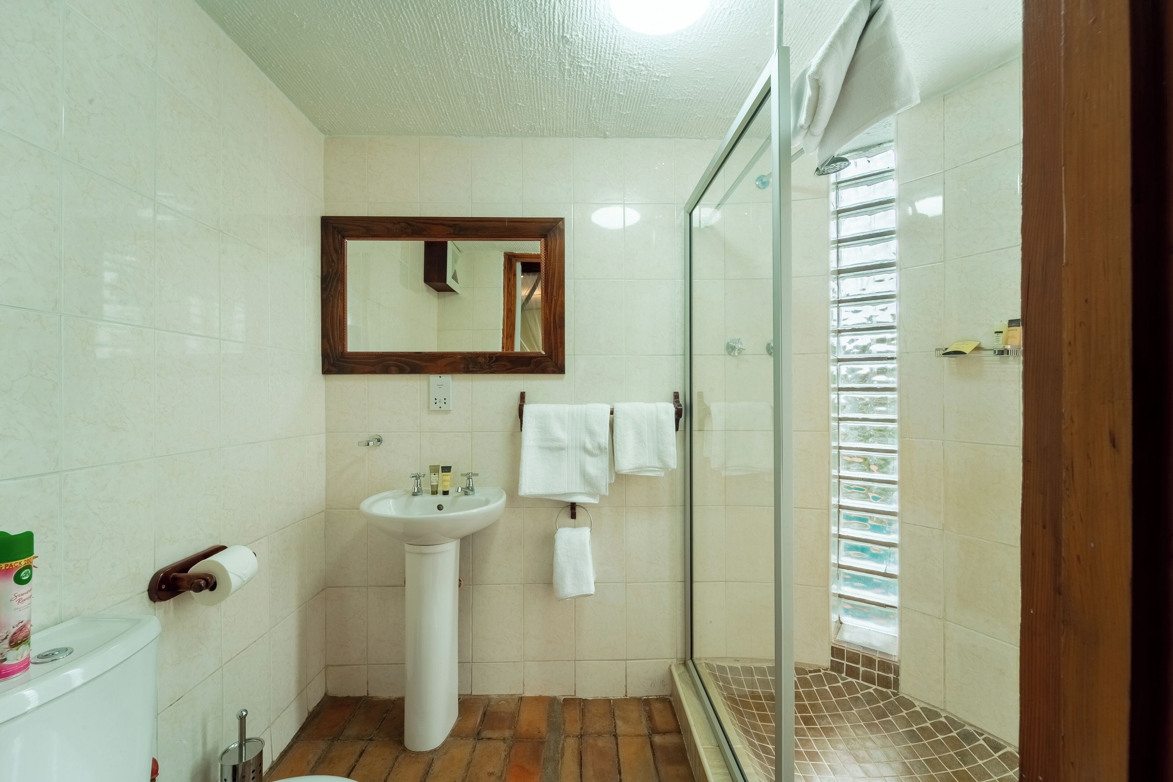A bathroom with a white sink, mirror, and glass shower enclosure.