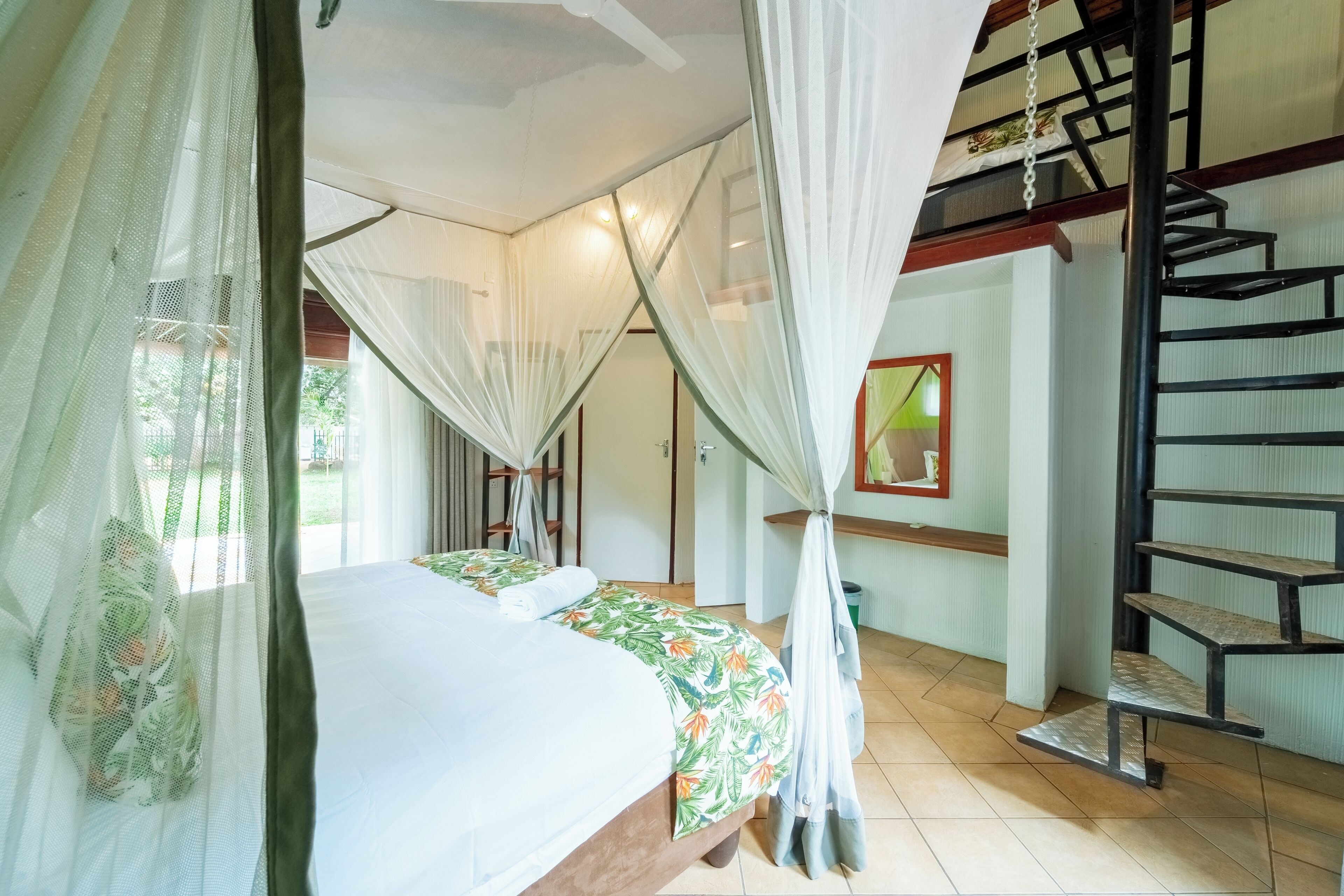 A room with a bed, a staircase, and a window with curtains.