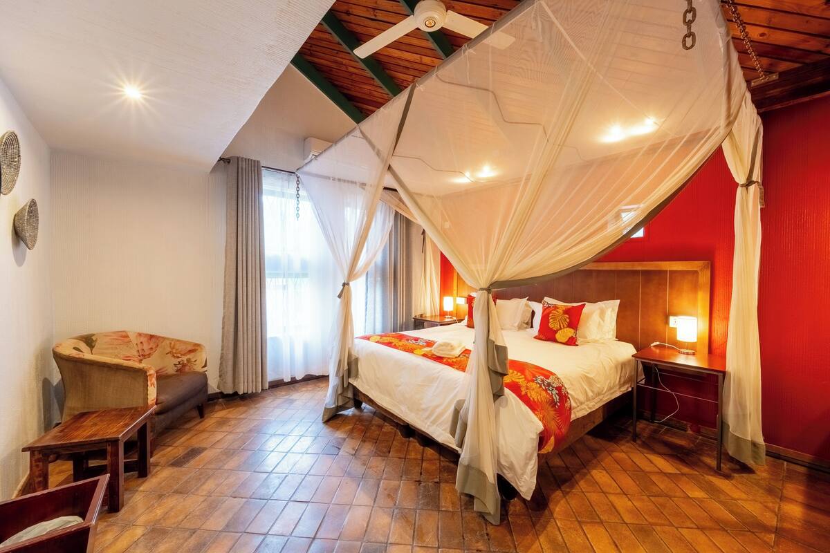 A room with a bed, a chair, a desk, and a ceiling fan.