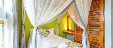 Quarto com cama sob dossel, paredes verdes e painéis de madeira.
