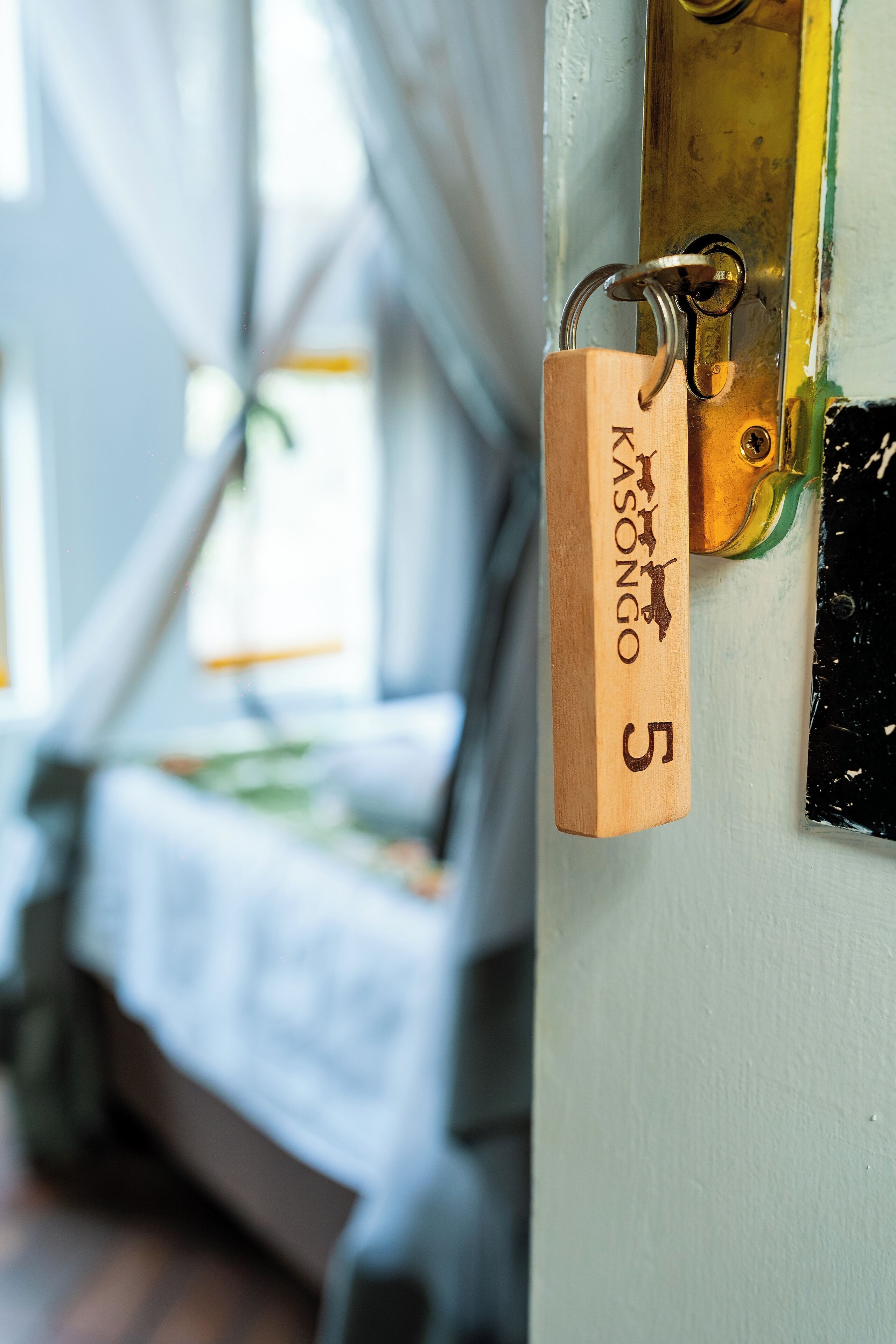 A close-up of a wooden padlock labeled "Kasongo 5" on a door.