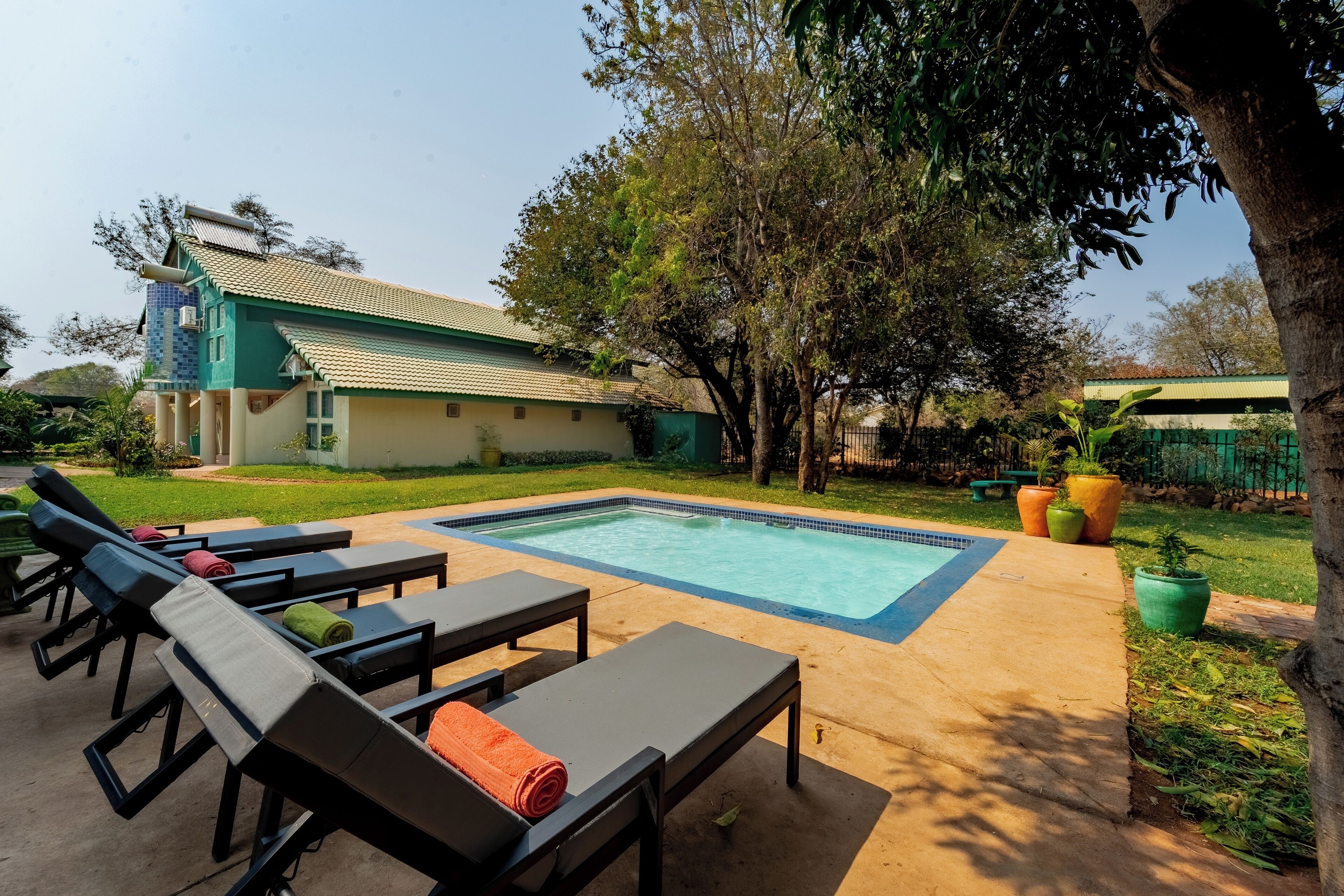 A pool area with lounge chairs and a building with a tiled roof.