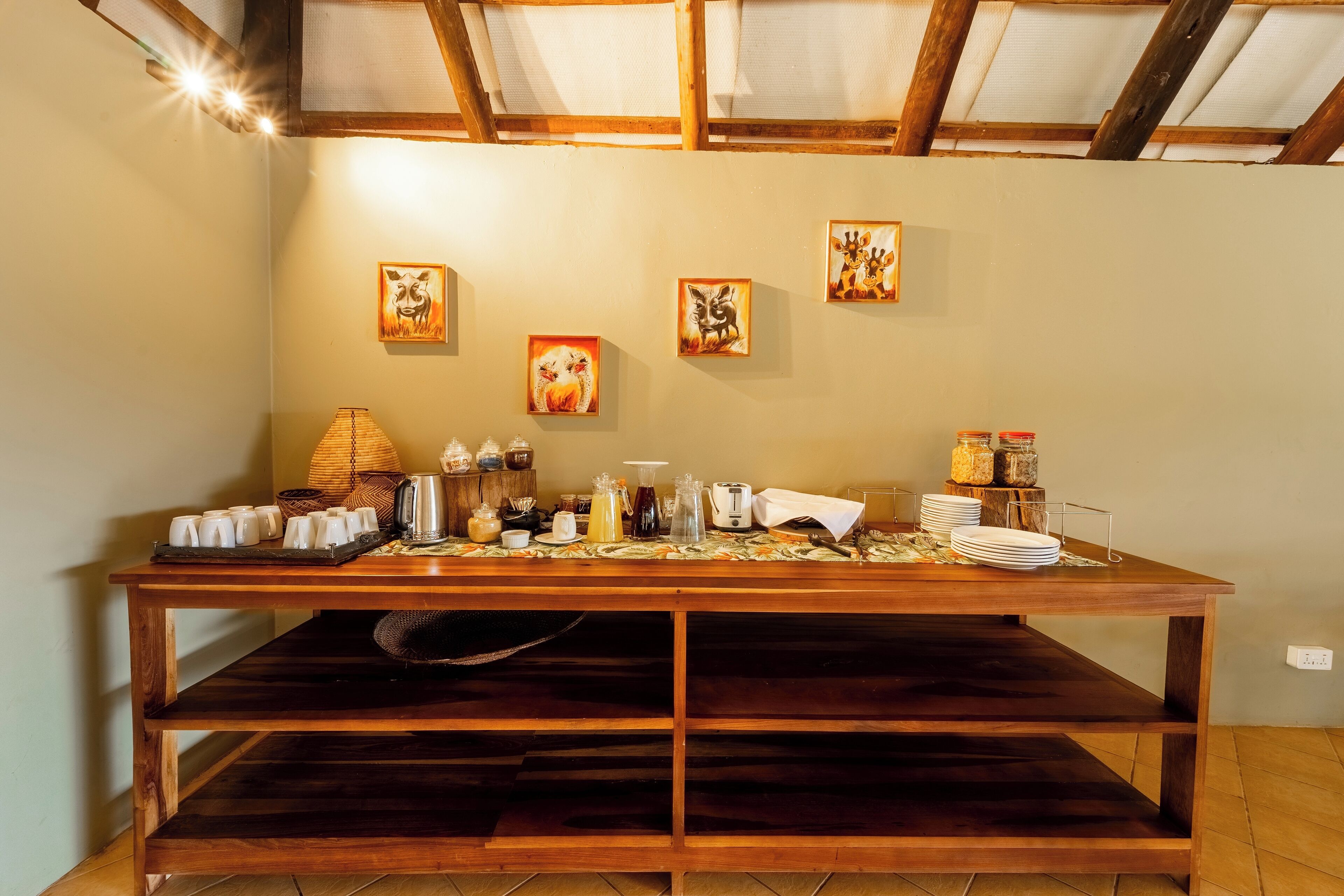 A wooden buffet table with various food items and condiments, set against a wall with framed artwork.