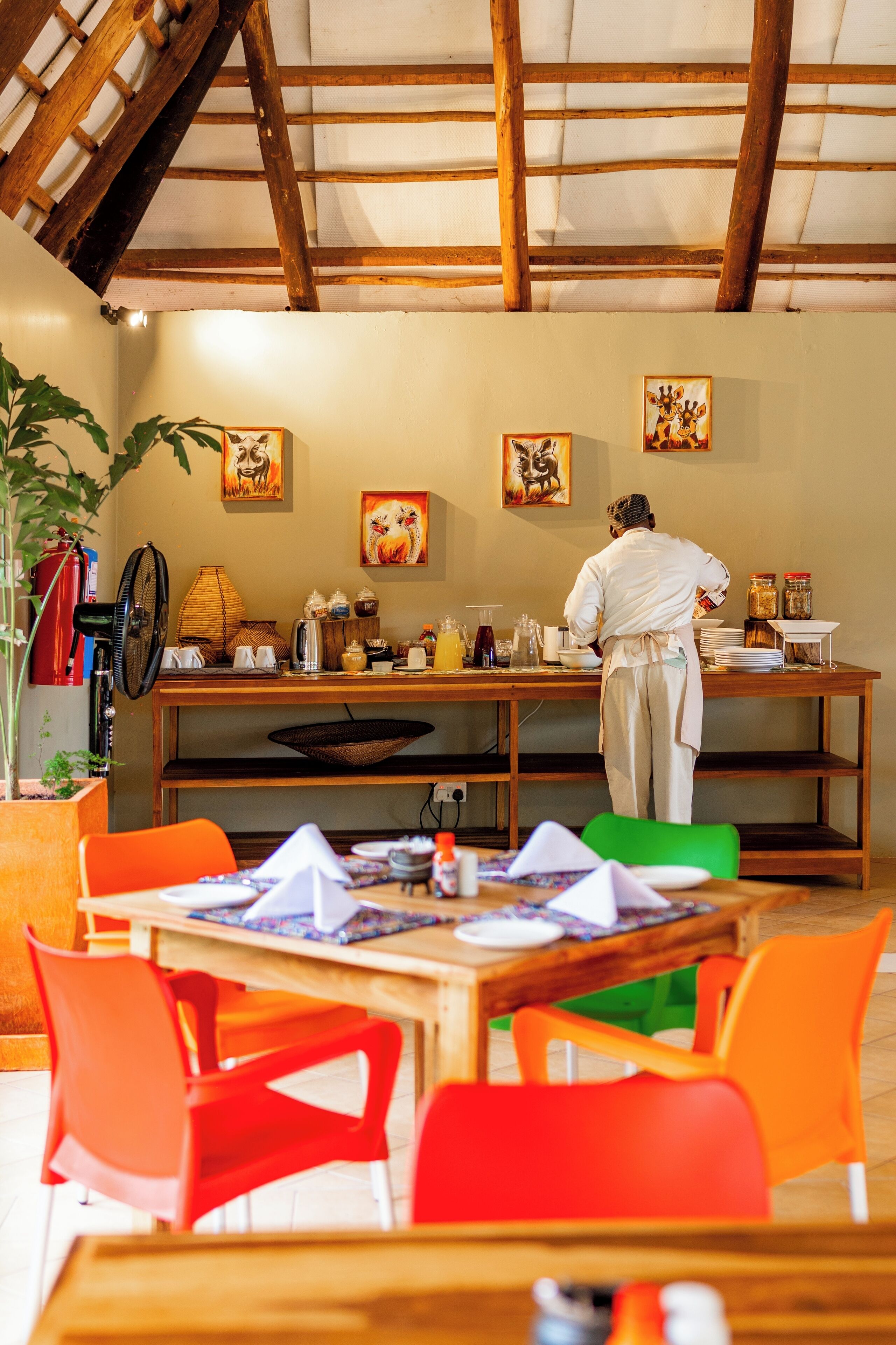 Un restaurant où un chef prépare les plats, avec des tables et des chaises en bois.