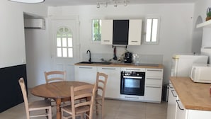 A compact kitchen with white cabinets, a wooden dining table, and a built-in oven. - House in Provence, 15 minutes from the beach, 20 minutes from Aix and Marseille. (Auriol)