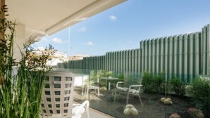 A modern outdoor patio with a glass wall, white chairs, and cacti. - Apartment 3 bedroom | ground floor| mountain view (La Caleta)