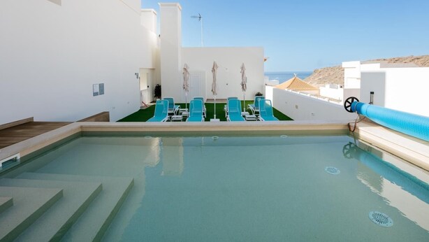 A rooftop pool area with blue lounge chairs and a clear view of the sea. - Apartment 2 bedroom | ground floor| mountain view (La Caleta)