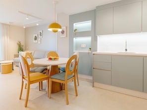A modern kitchen with a round dining table, wooden chairs, and a pendant light.