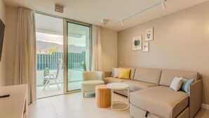 A modern living room with a sofa, armchairs, a small table, and a sliding glass door leading to a balcony. - Apartment 2 bedroom | ground floor| mountain view (La Caleta)