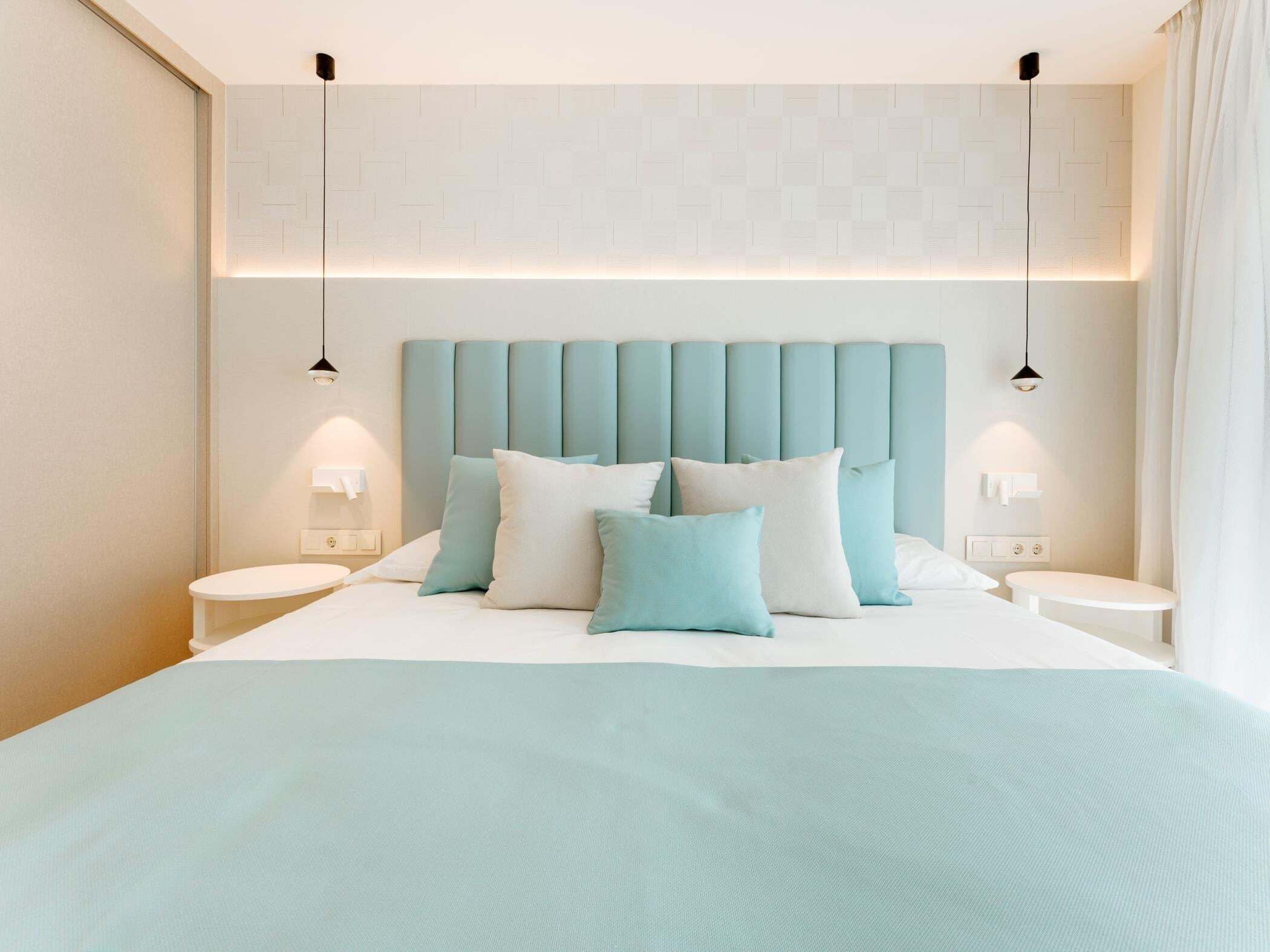 Ein modernes Hotelzimmer mit einem großen Bett, zwei Nachttischen und einer Wandleuchte.