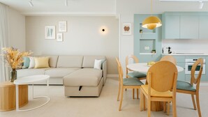Un salon moderne comprenant un canapé, une table à manger et des chaises. Il y a également un coin cuisine avec des placards et un plan de travail.