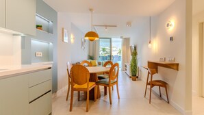 Una cocina moderna con comedor, que incluye una isla grande, sillas de madera e iluminación colgante.