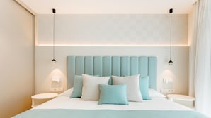 Une chambre d’hôtel moderne dotée d’un grand lit, de deux tables de chevet et d’une tête de lit avec éclairage intégré.
