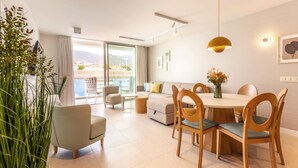 Un soggiorno moderno con zona pranzo, ampie finestre e vista su piscina e montagne.