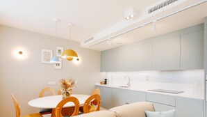 Eine moderne Küche mit weißer Arbeitsplatte, Spüle und einem Essbereich mit rundem Tisch und Holzstühlen.