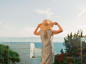 A person standing on a balcony with a view of the sea.