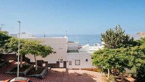 Un quartier résidentiel situé sur la côte, avec une cour dallée, des bâtiments blancs et une vue dégagée sur la mer.