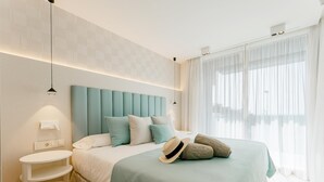 Une chambre à coucher moderne, avec un lit, des tables de chevet et une vue sur l’extérieur.