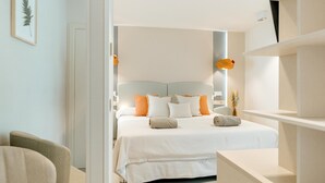 A modern bedroom with a large bed, white bedding, and orange pillows.