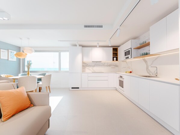 A modern kitchen with white cabinetry, a marble backsplash, and a built-in oven. - Exclusive penthouse with sea view in La Caleta (La Caleta)