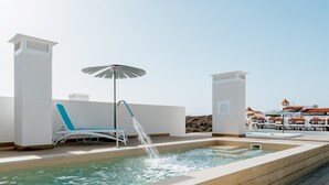 Ein Pool auf dem Dach mit einer Springbrunnen, einer Liege und einem Sonnenschirm.